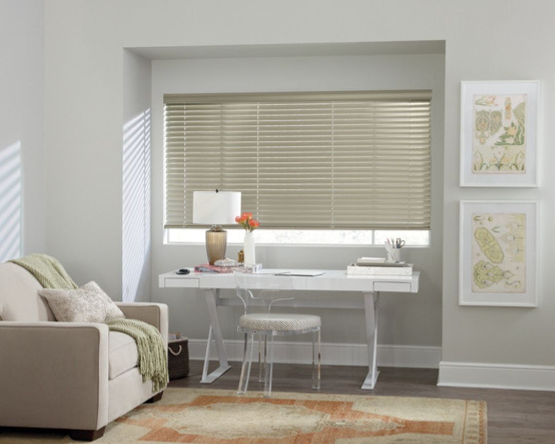A living room with a couch , desk , chair and blinds.