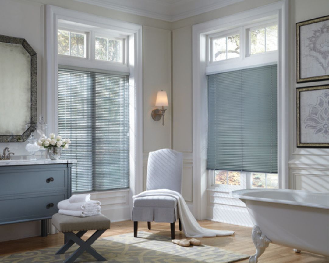 A bathroom with a tub , sink , chair and mirror.
