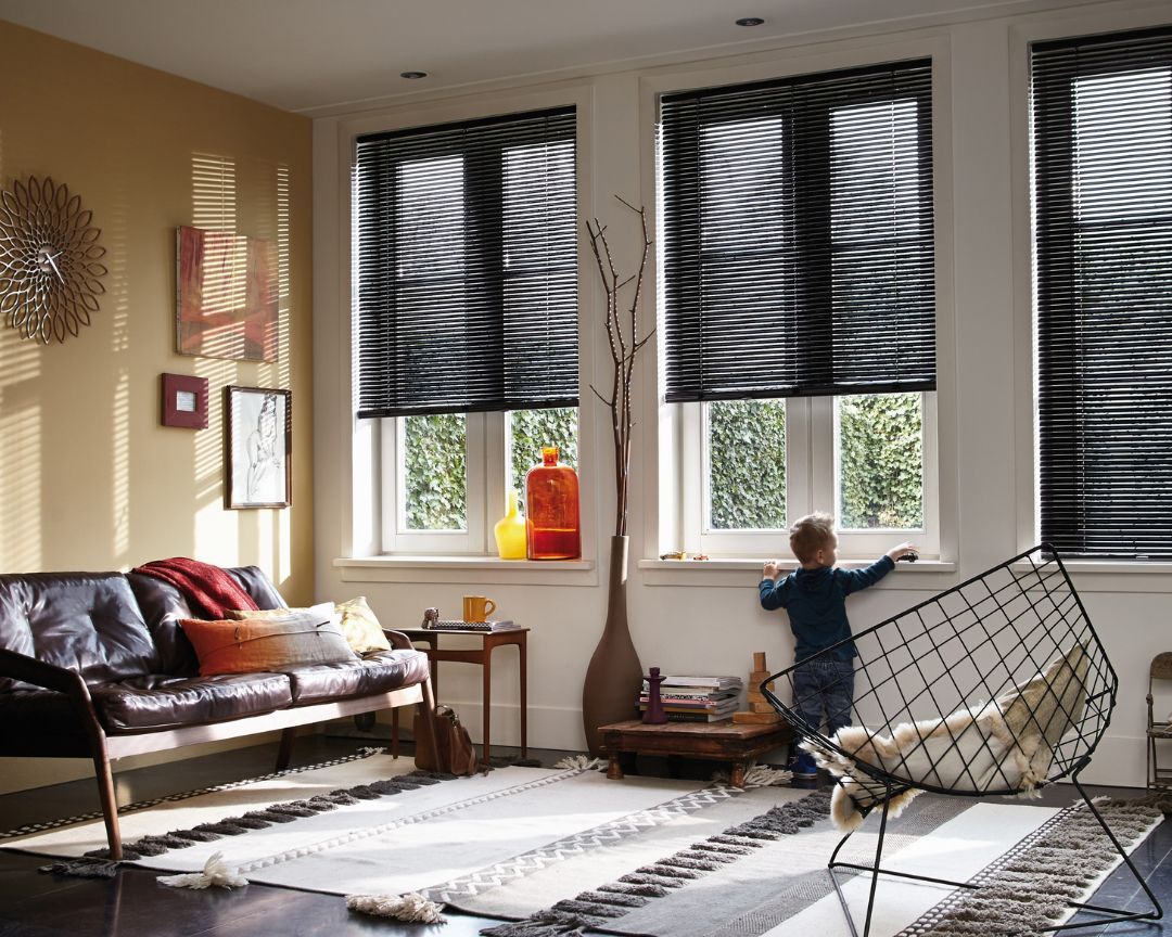 A little boy is standing in a living room looking out of a window.