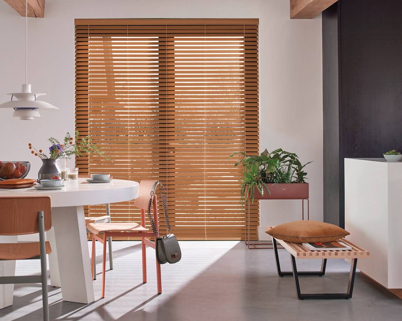 A dining room with a table and chairs and wooden blinds on the windows.