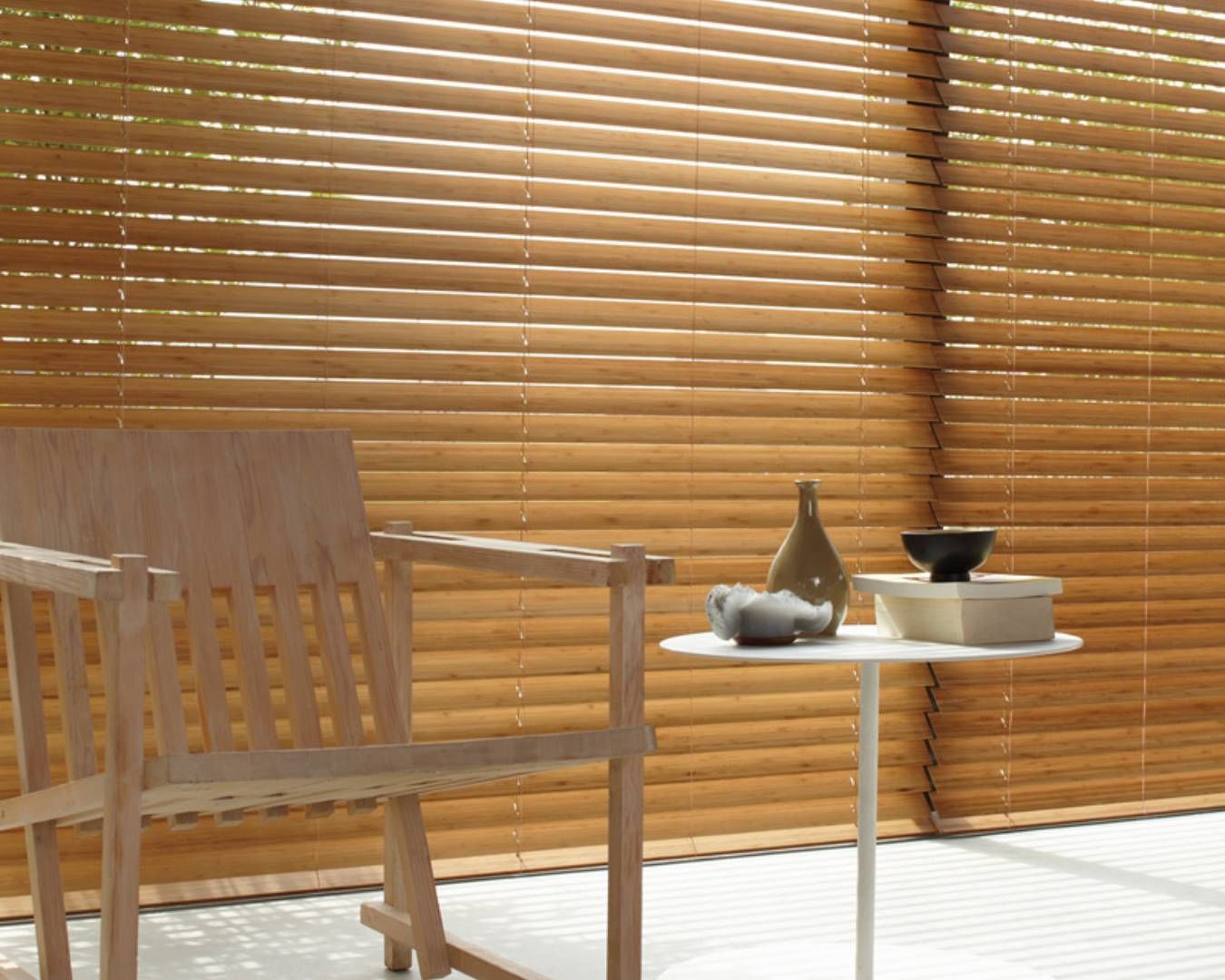 A wooden chair sits in front of a window with wooden blinds