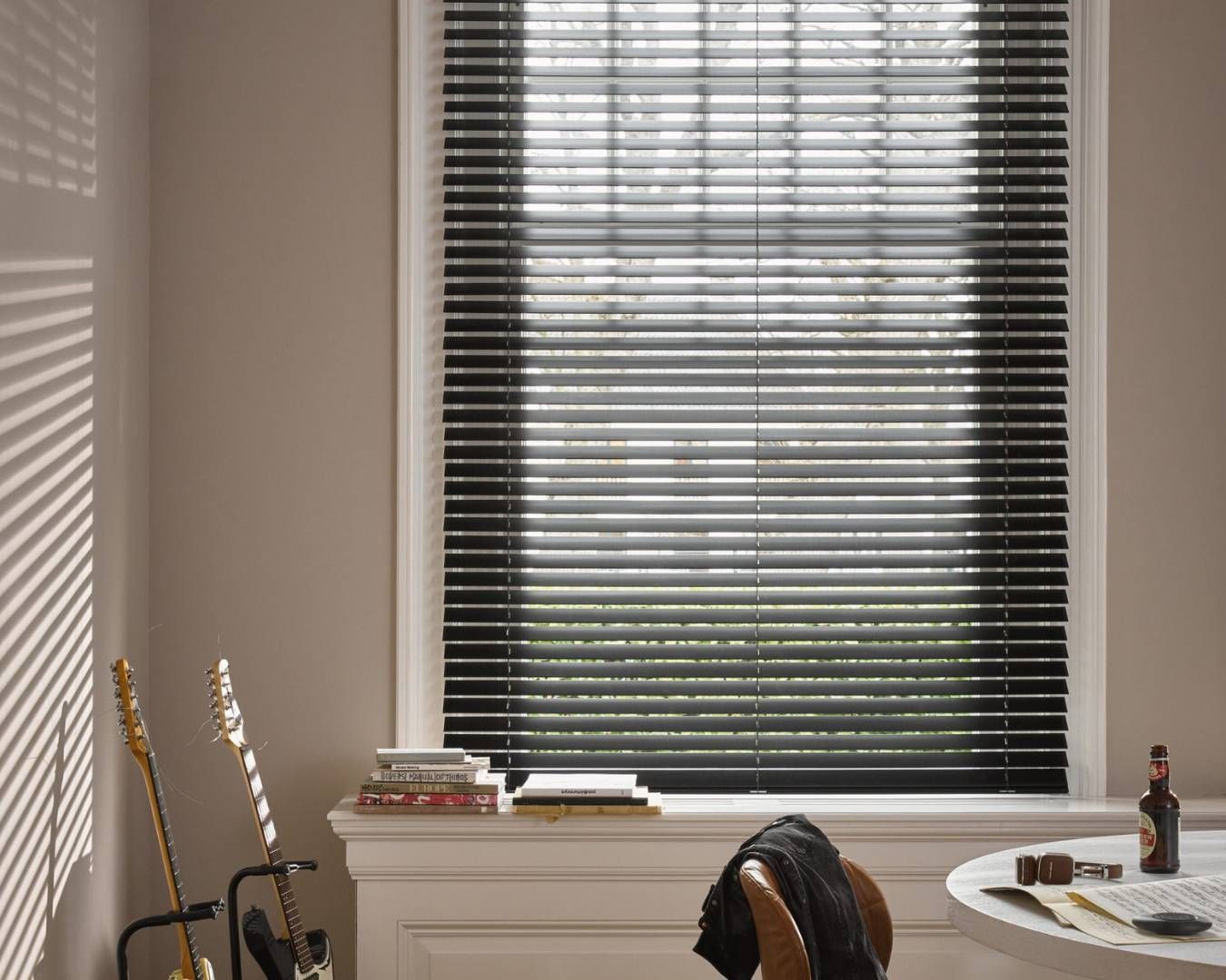 A room with a desk and a window with blinds.