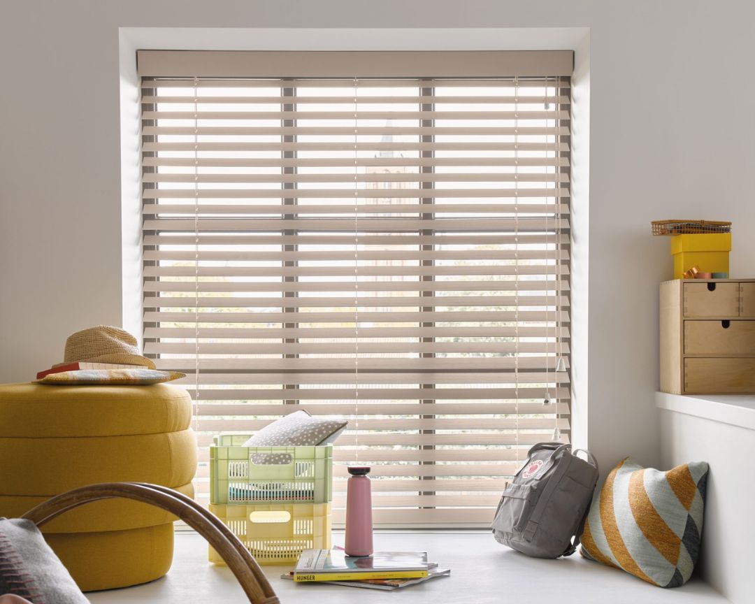 A living room with a large window and wooden blinds.