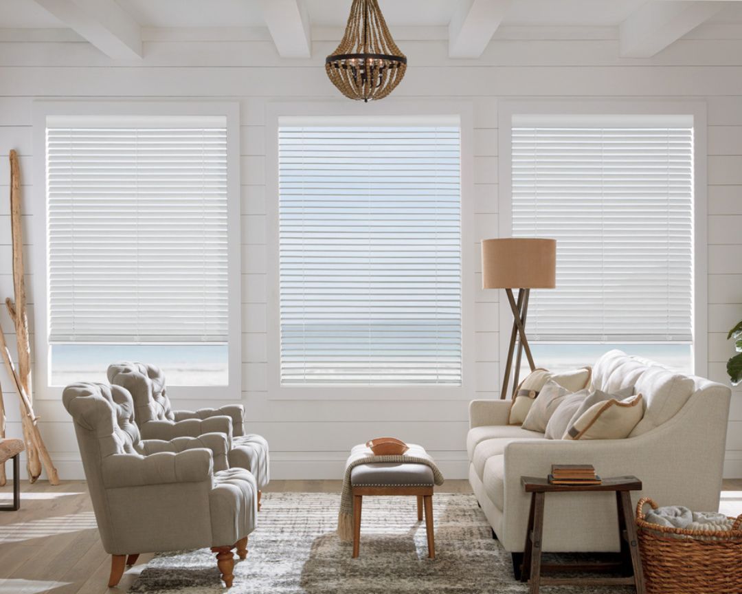 A living room with a couch , chairs , and a chandelier and blinds