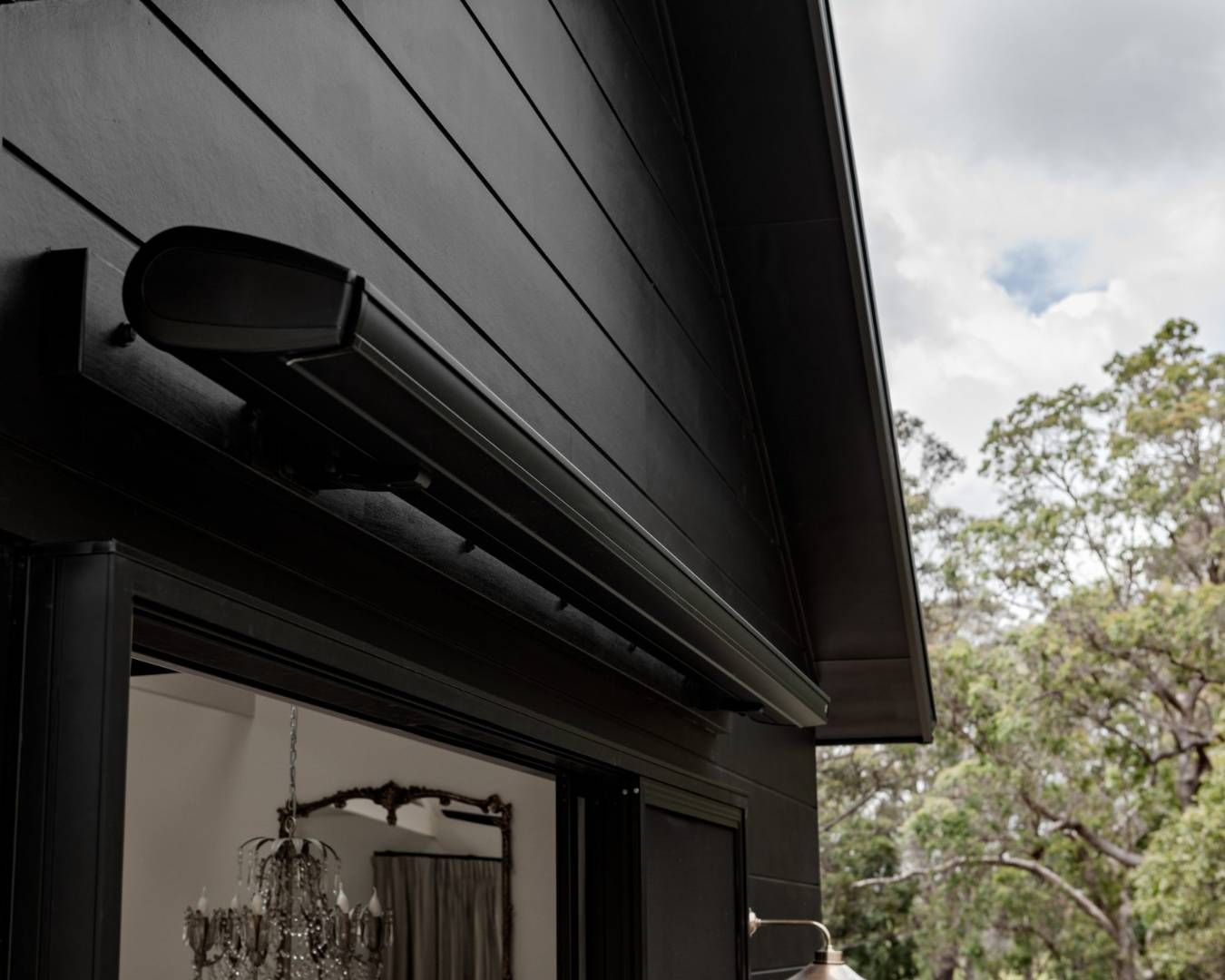 Close-up view of a retractable awning attached to a modern black house exterior.