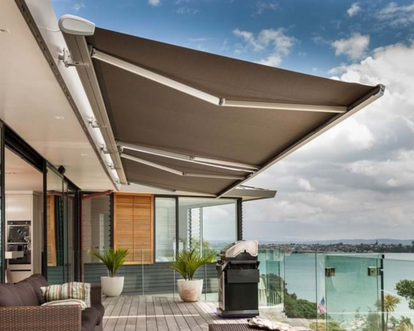 Contemporary home with a retractable awning, overlooking a scenic waterfront view.
