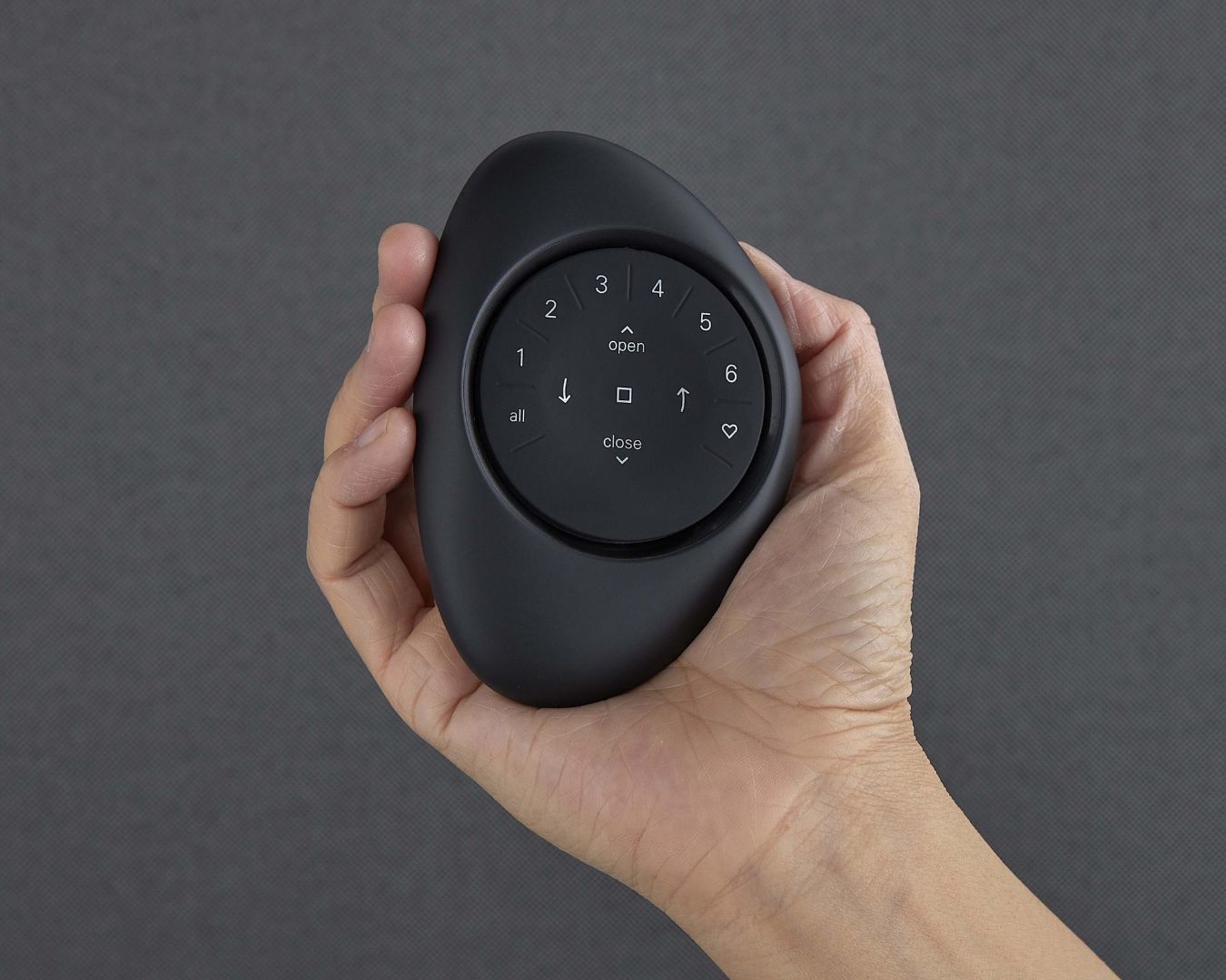 A person is holding a black remote control with the numbers