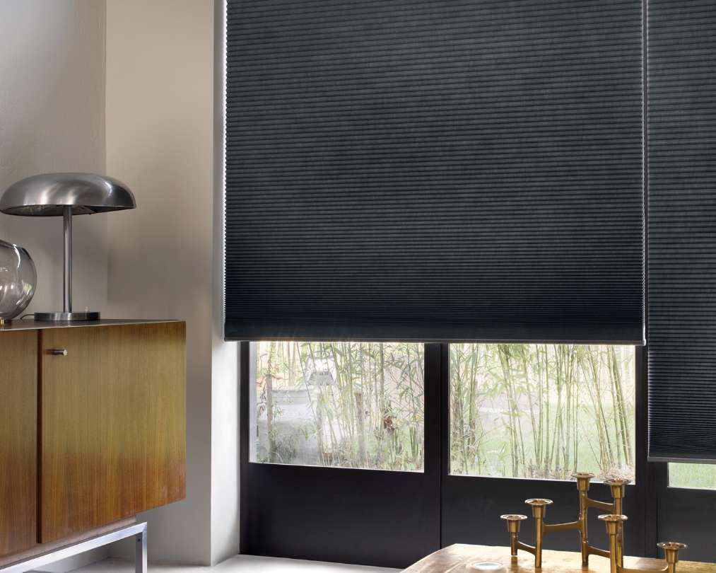 A living room with a large window and black blinds