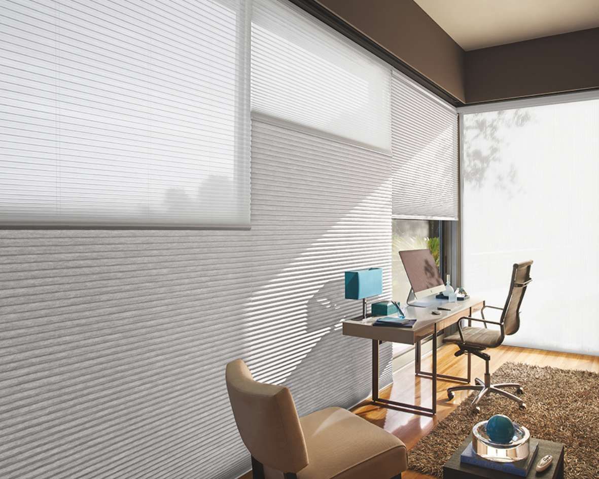 A home office with a desk and chairs and a large window