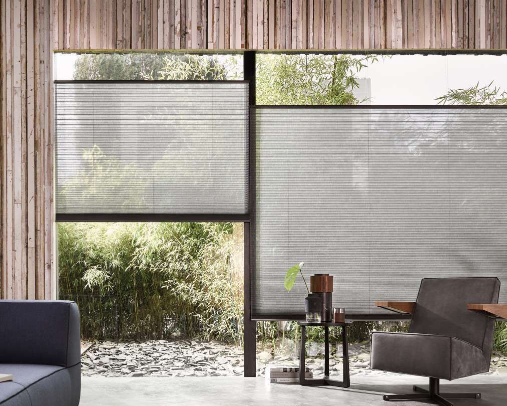 A living room with a couch , chair , table and window with blinds.