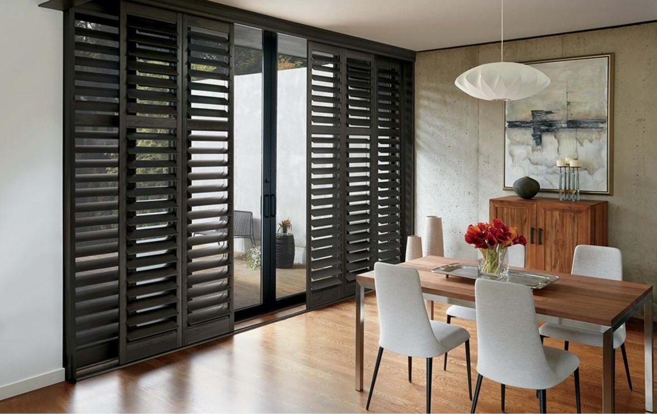A dining room with a table and chairs and sliding glass doors.