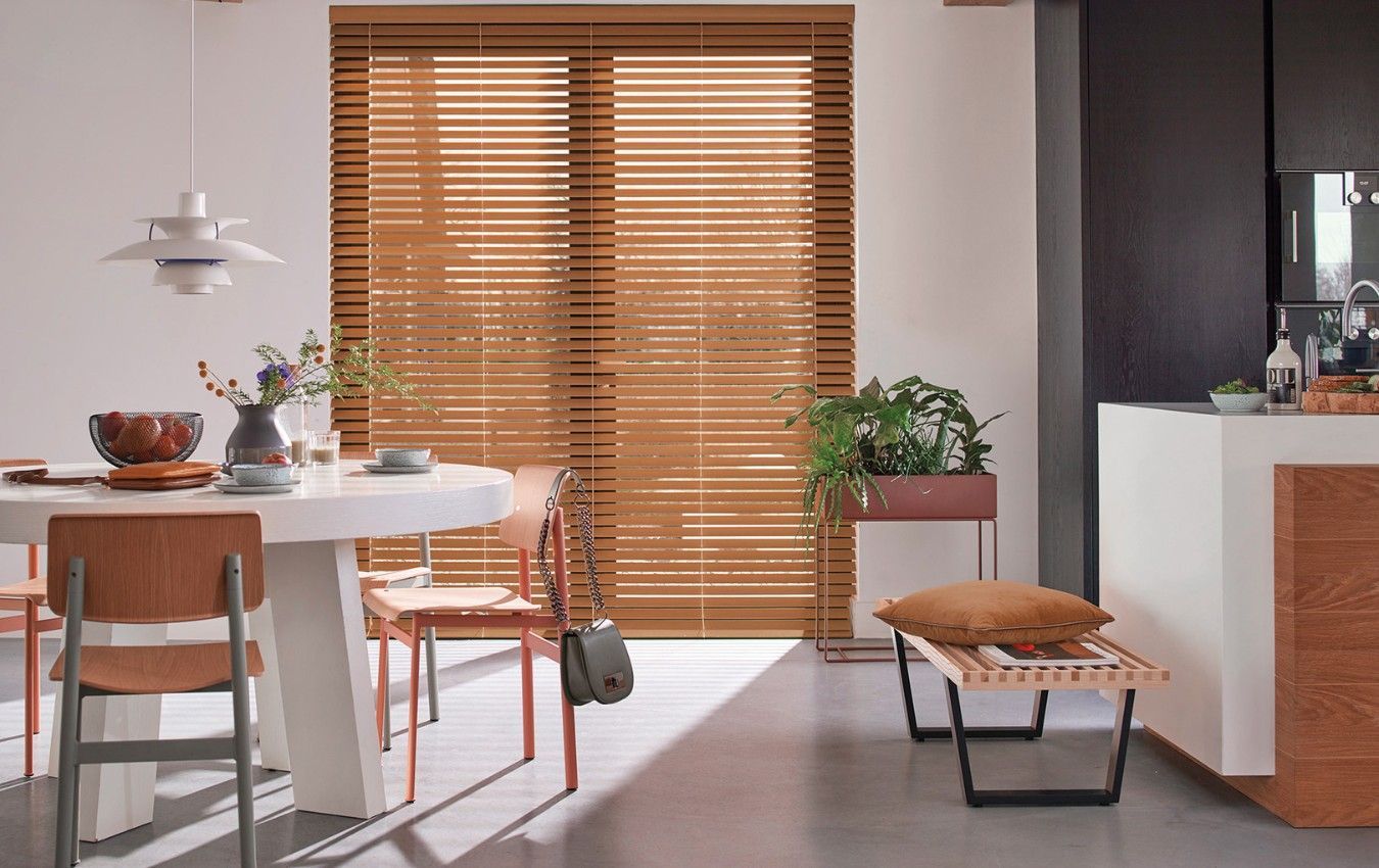 Cozy kitchen and dining area with wooden Venetian blinds, a dining table, and modern decor.