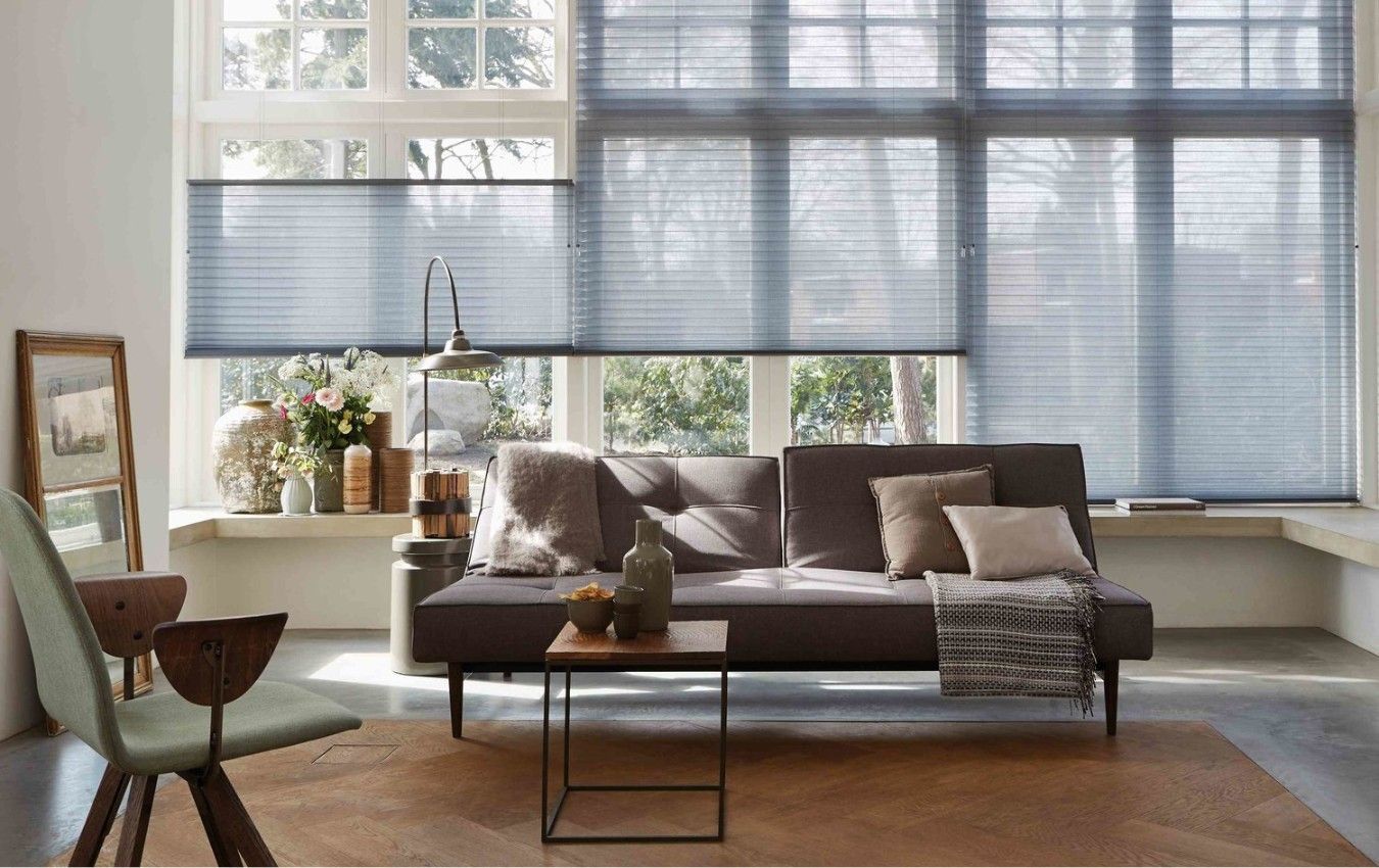 A living room with a couch and a table in front of a window with blinds