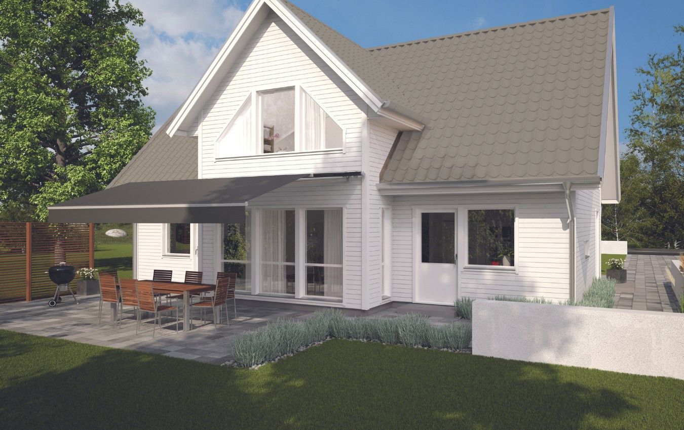 A white house with a brown roof and a patio with a table and chairs.