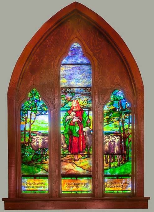 A stained glass window shows a woman holding a lamb