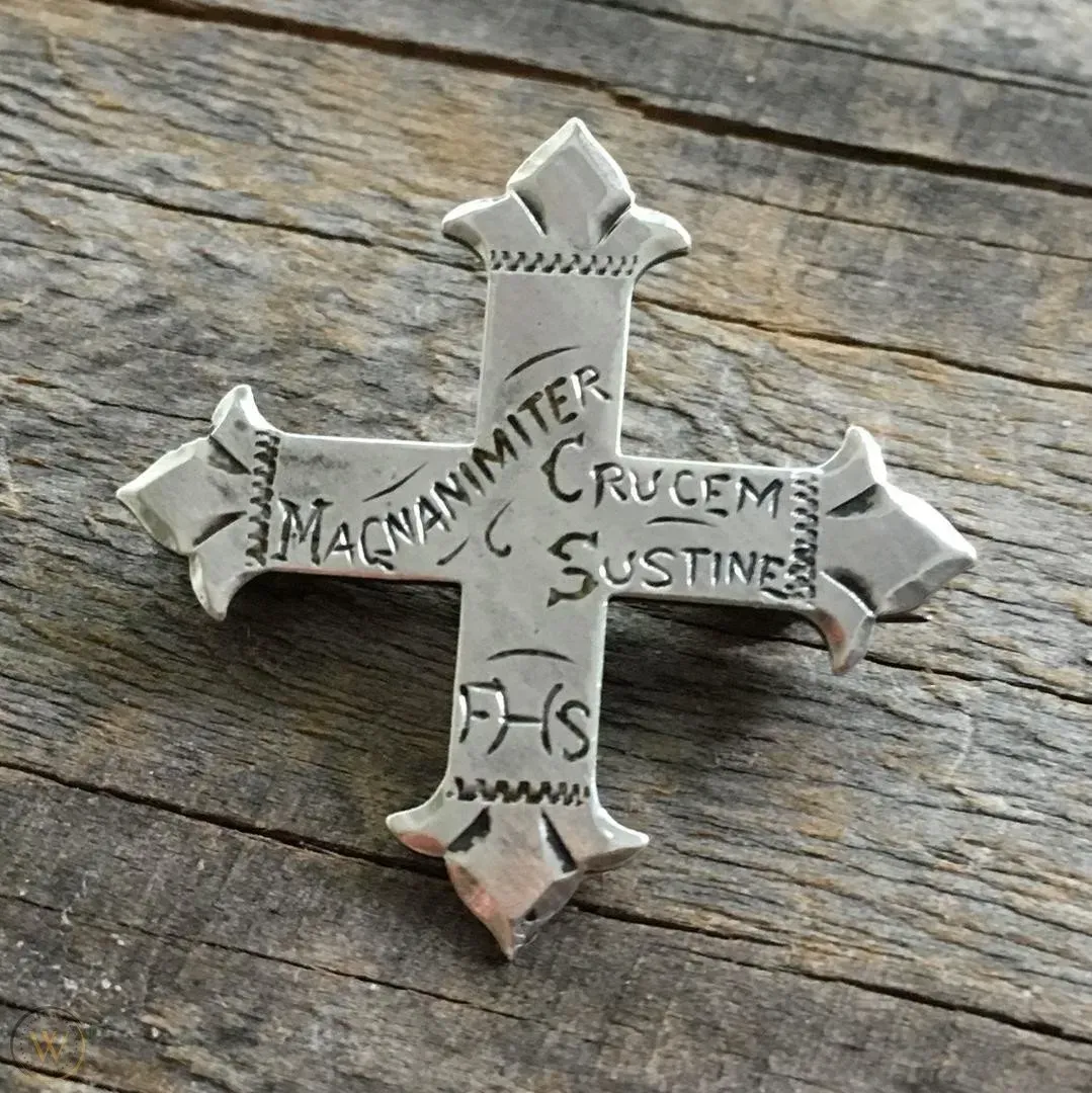 A silver cross is sitting on a wooden table.