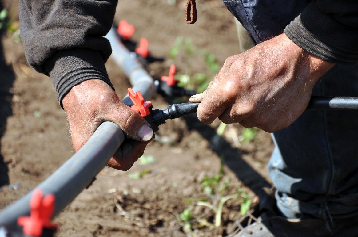 A Man is Working on a Hose in the Dirt — Wade N Water In Inverell, NSW