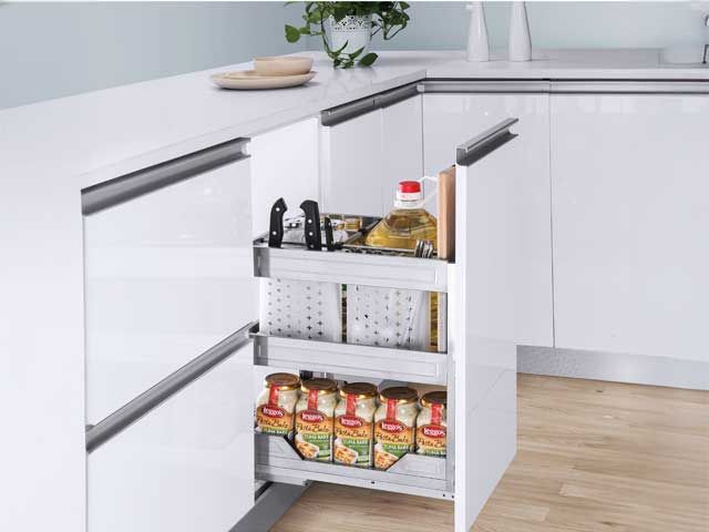 Estante extraíble para despensa de cocina con condimentos y frascos en un armario esquinero blanco.