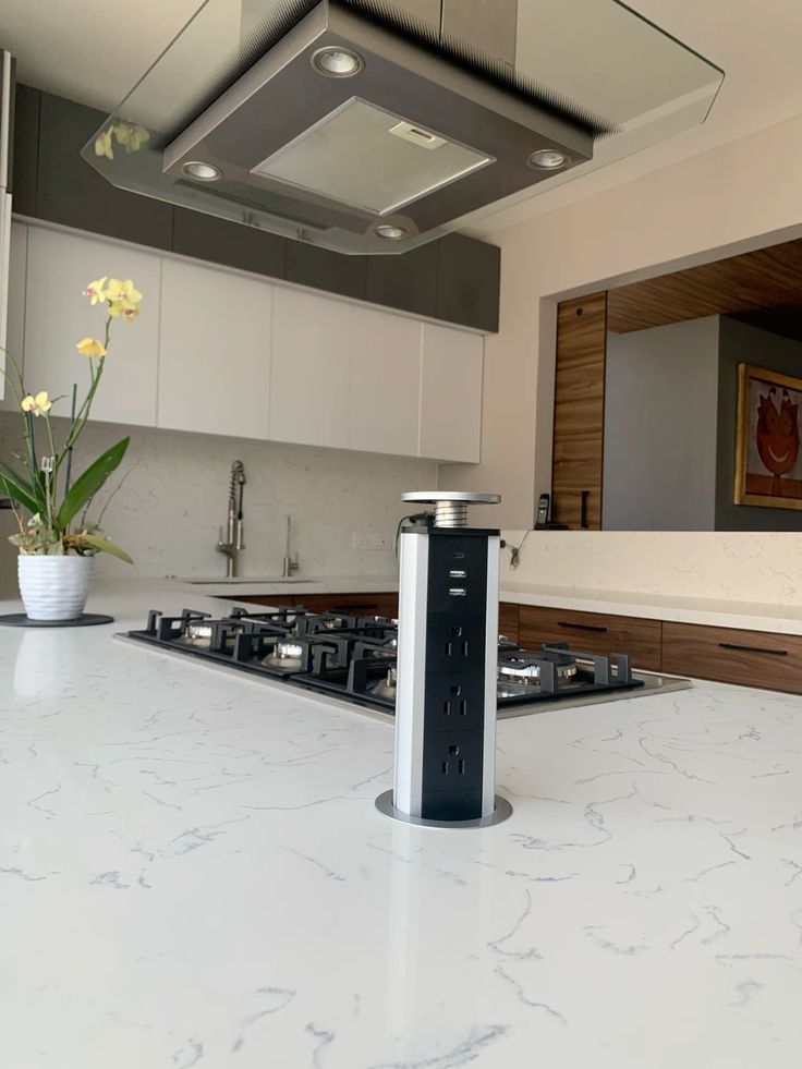 Isla de cocina moderna con elemento cilíndrico negro y encimera de mármol blanco.
