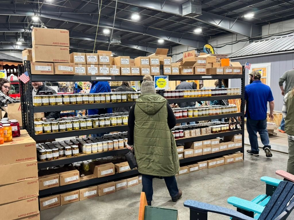 Shelves stocked with jars of food and boxes, customers browse in a market.