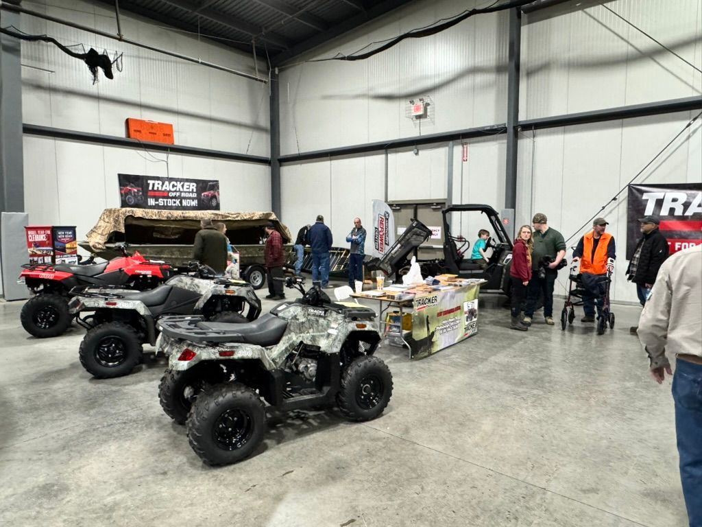 ATV vehicles on display at an indoor trade show with people browsing.