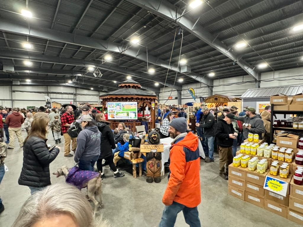 Indoor market with many people, booths, food items, and a gazebo.