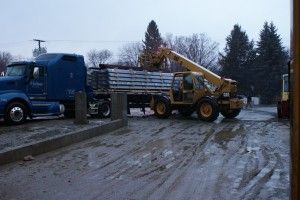 Blue truck and yellow loader on a muddy road at a rural work site