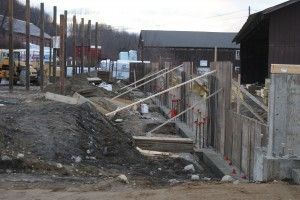 Construction site with wooden stairs and railings beside a dirt path and buildings