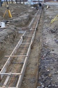 Workers installing rebar in a long trench at a construction site