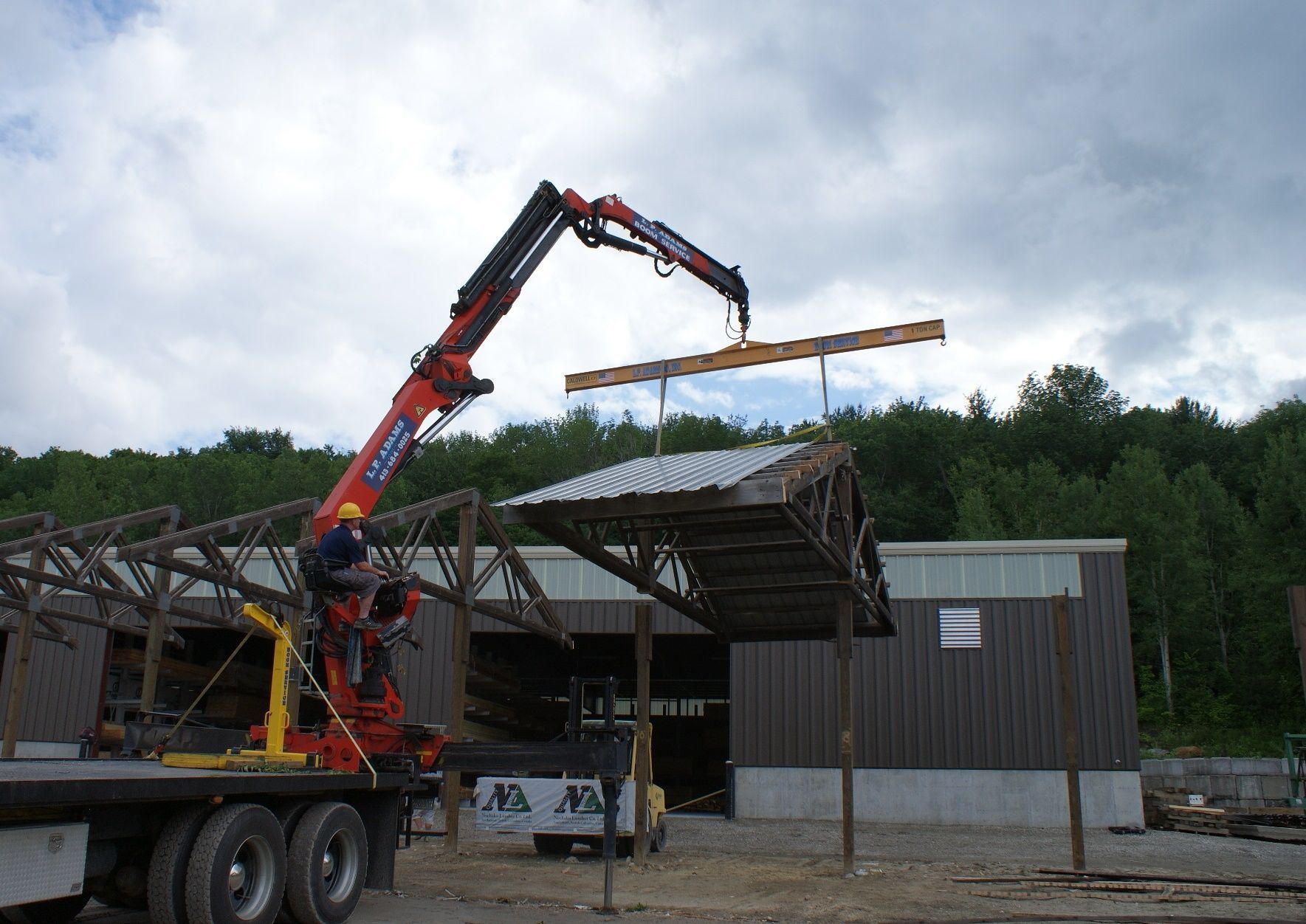 Crane lifting a long beam onto a building roof at a construction site