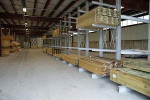 Warehouse interior with stacked lumber bundles on metal racks and concrete floor