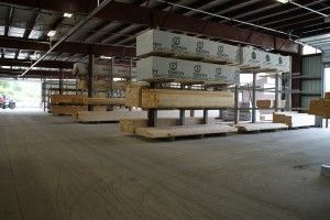 Warehouse with stacked lumber bundles on a raised platform under a metal roof.