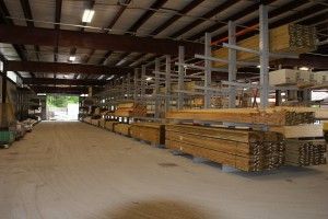 Interior of a large warehouse with stacked lumber and metal shelving racks