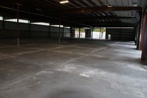 Empty industrial warehouse with a concrete floor and metal roof beams