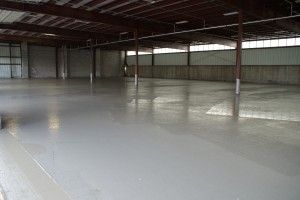 Empty warehouse interior with a smooth gray floor and metal beams