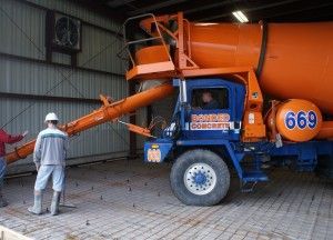 Worker beside blue-orange cement mixer truck in a warehouse
