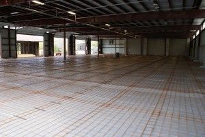 Empty warehouse interior with concrete floor, exposed beams, and open doorway