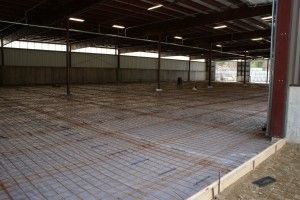 Empty indoor warehouse with metal roof, concrete floor, and open sides under construction