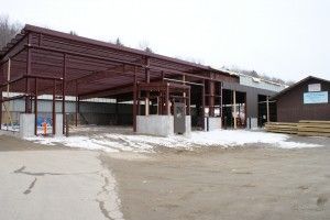 Snowy industrial building under construction with steel framing and concrete walls
