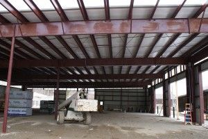Empty steel-framed warehouse interior with exposed roof beams and concrete floor