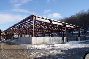 Partially built steel-frame structure on a snowy lot under a clear sky