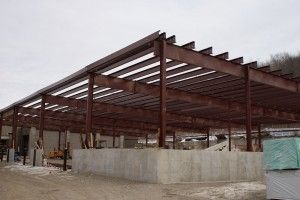 Steel-framed building under construction with concrete walls and gravel foreground
