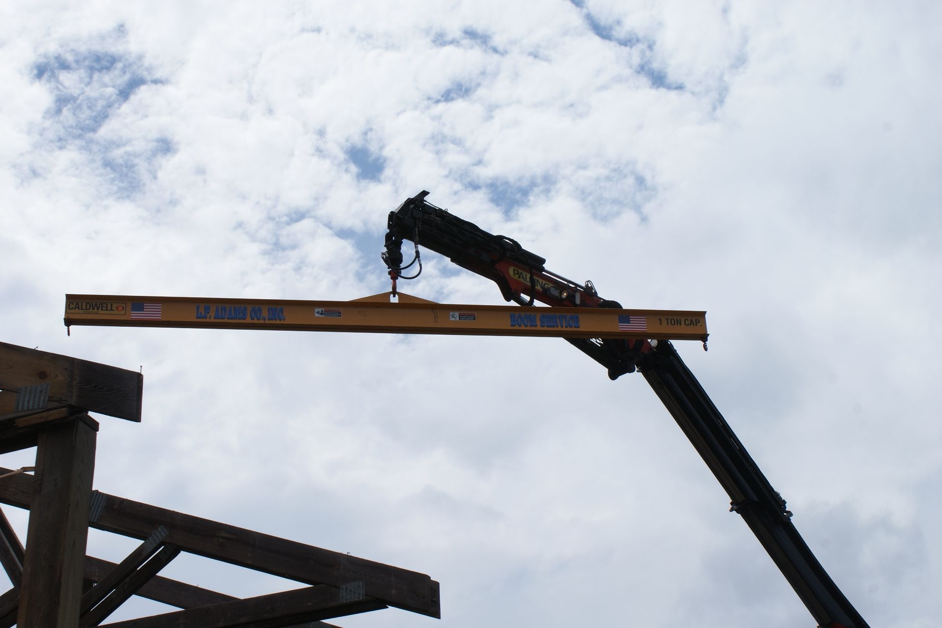 Construction crane lifting a steel beam against a cloudy sky