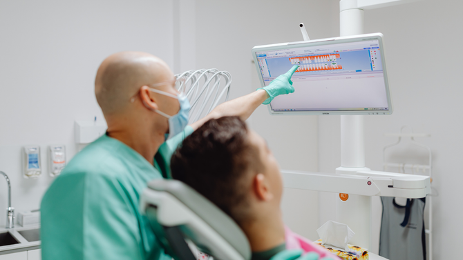 Dentist holding shade guide near smiling patient in a dental clinic