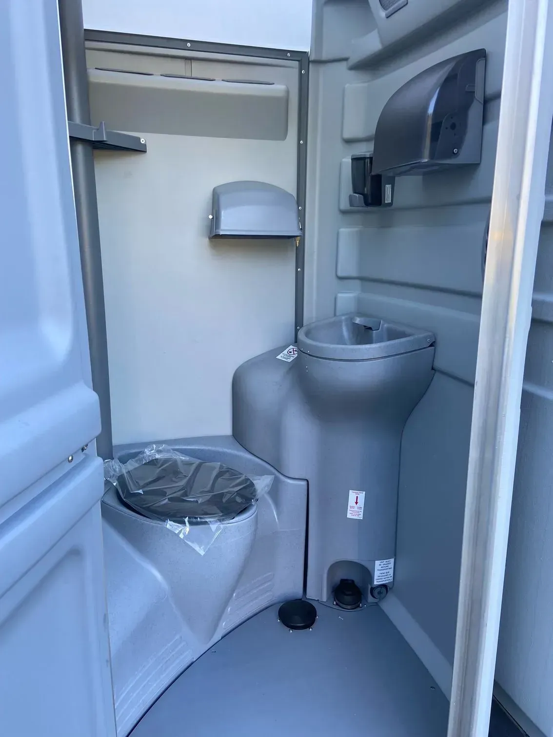 Compact public restroom interior with toilet, sink, paper towel dispenser, and trash can