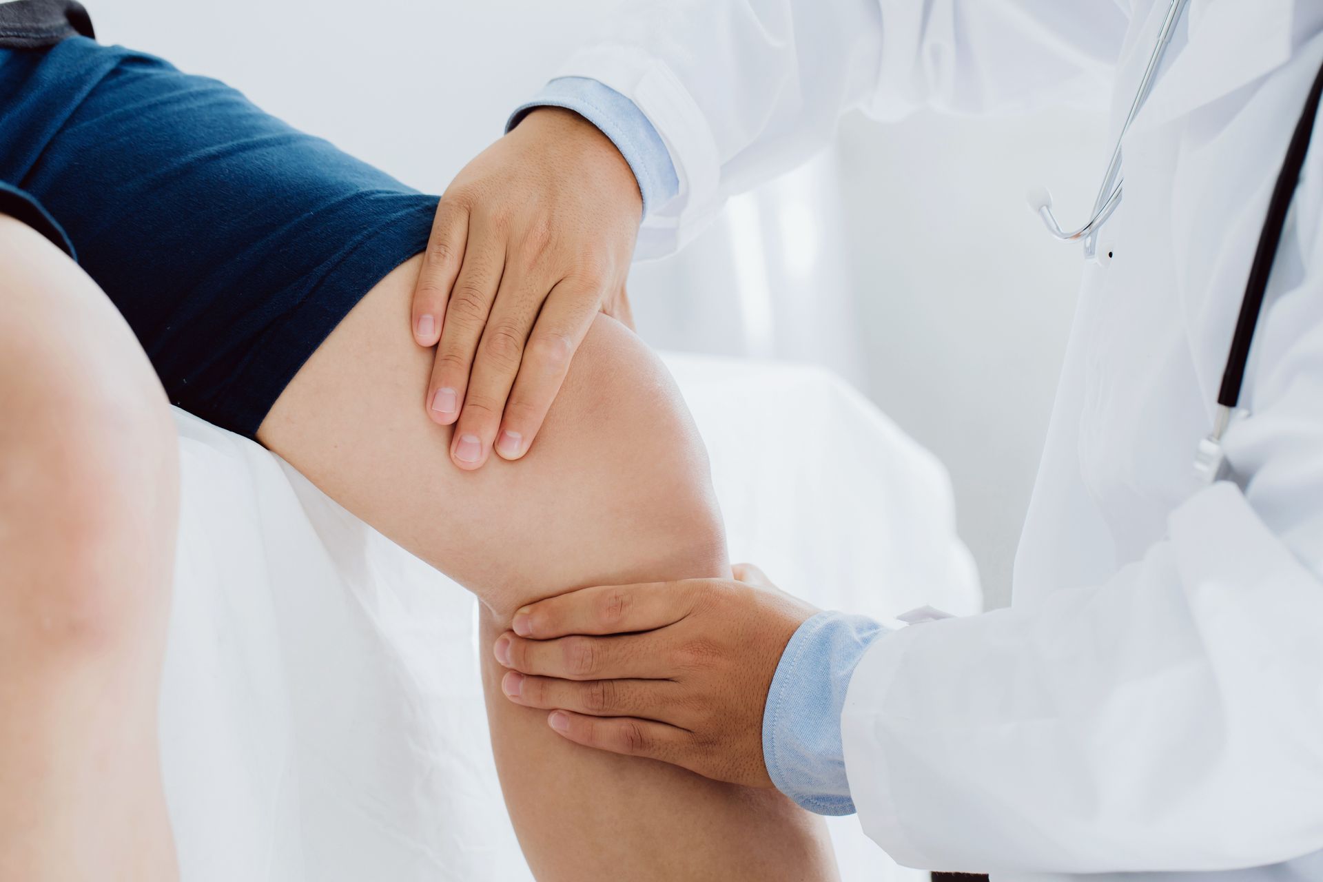 Médico examinando o joelho de um paciente em um ambiente clínico.