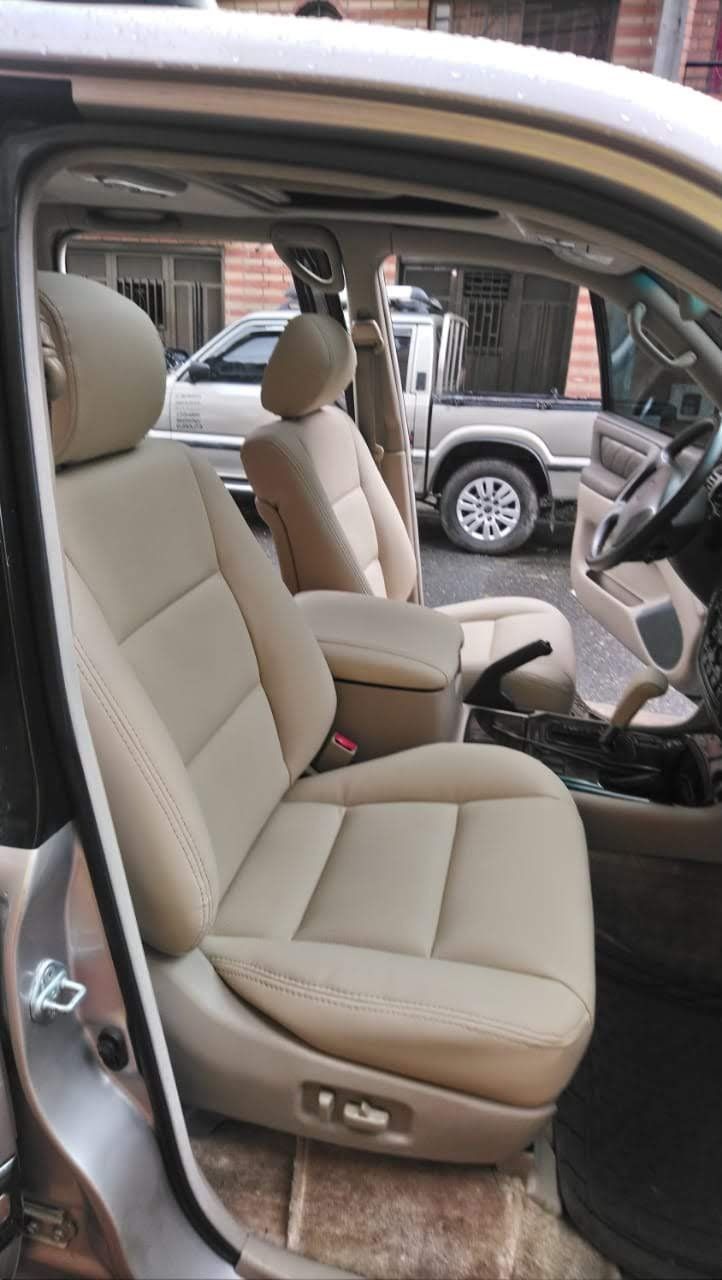 El interior de un coche con asientos de cuero beige y un volante.