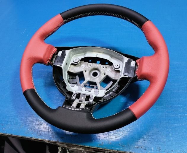 Un volante rojo y negro está sobre una superficie azul.