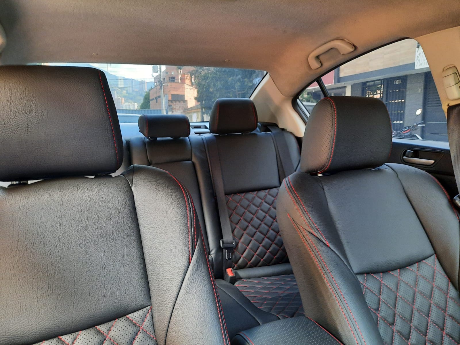 El interior de un coche con asientos de cuero negro y costuras rojas.