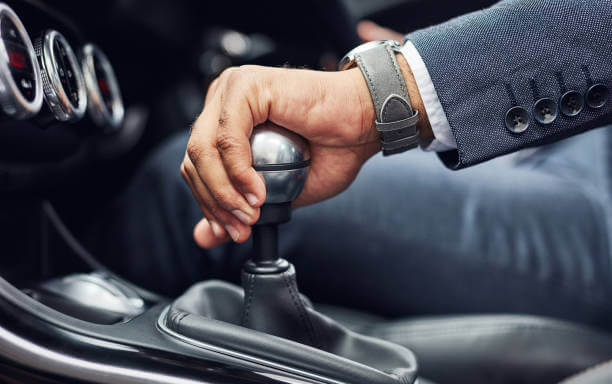Un hombre con traje está cambiando de marcha en un coche.